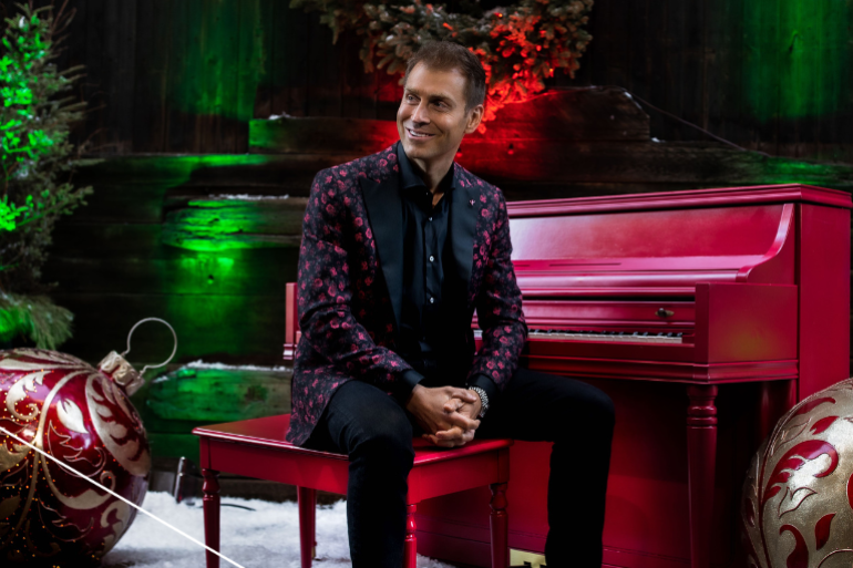 Musician Phil Thompson sitting at a piano with holiday decor around him
