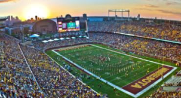Aerial view of the University of Minnesota's filled football stadium as the sun sets in the horizon.